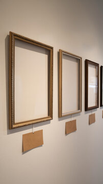 Empty framed artworks and blank information plaques displayed along a softly lit gallery wall creating a refined museum interior with clean space for exhibitions and cultural presentations
