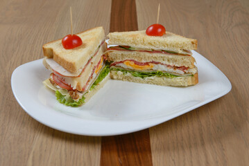 Two sandwiches on white plate: a hearty and delicious lunch or snack featuring layers of fresh ingredients