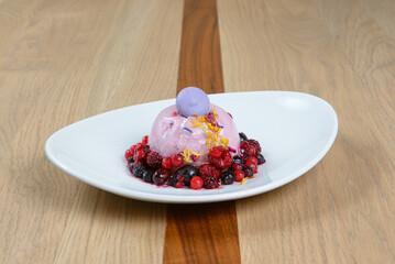 Elegant berry dessert: Creamy dome surrounded by fresh mixed berries presented on a modern white plate