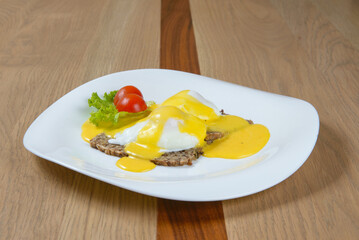 Eggs Benedict: Poached eggs hollandaise sauce on multigrain bread garnished with lettuce and tomatoes