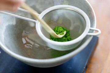 Closeup of fresh matcha powder, green tea powder, Chashaku, matcha scoop and Chawan, matcha bowl.