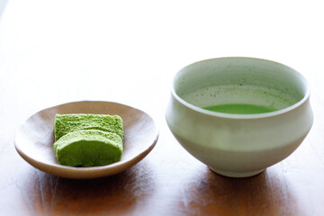 Cup of fresh matcha tea and Warabi mochi, traditional Japanese sweet from bracken starch on wooden table.