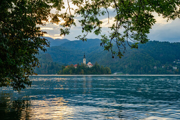 Bled castle in lake and sunset in the background with plants frame