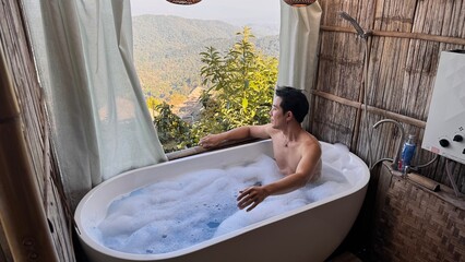Handsome Asian Male Model Relaxing in Bathtub with Stunning Mountain View