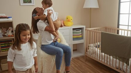 Woman plays with son and daughter in cozy bedroom with crib, showing love and happiness in a family home setting, highlighting a nurturing environment.