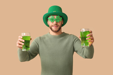 Young man in leprechaun hat with glasses of beer on brown background. St. Patrick's Day celebration