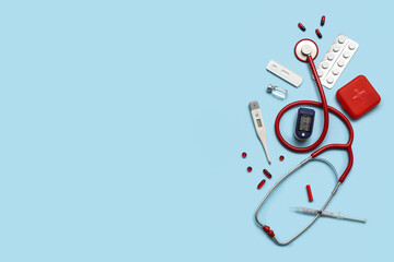 Composition with pulse oximeter, stethoscope, thermometer and medicines on blue background