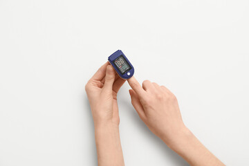 Female hands with pulse oximeter on white background