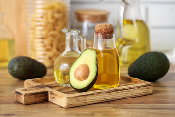 Bottle and jug of fresh avocado oil on wooden table