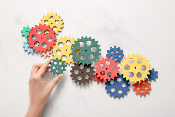 Hand with wooden gears on light background