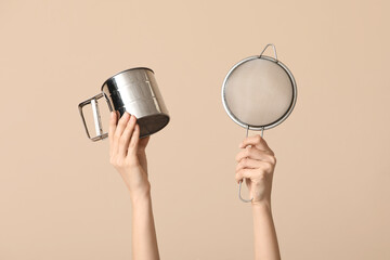 Female hands with sieves on beige background