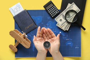 Woman holding compass with wooden plane, money, map and magnifier on yellow background. Itinerary...
