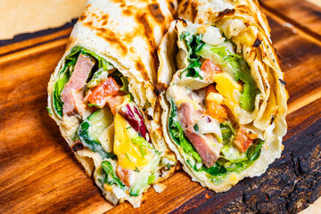 Delicious wrap filled with fresh ingredients on wooden platter
