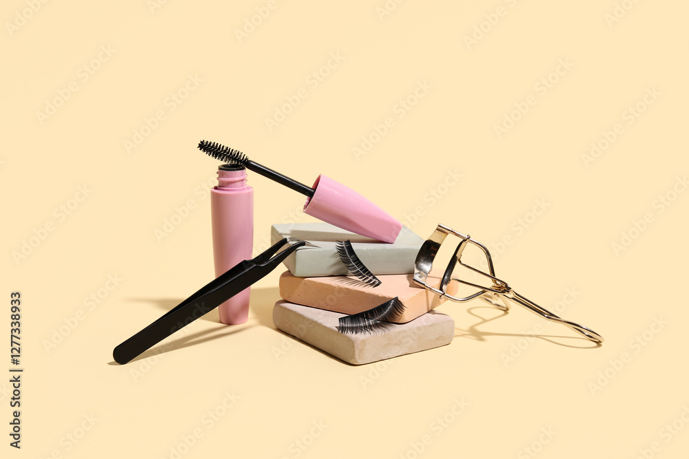 Wall mural Plaster podiums with false eyelashes, curler, tweezers and mascara on beige background