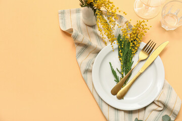 Beautiful table setting with mimosa flowers on orange background