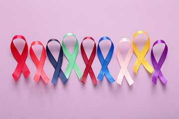 Row of different ribbons on lilac background. World Cancer Day