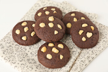Tasty chocolate cookies with hazelnuts on white table, closeup