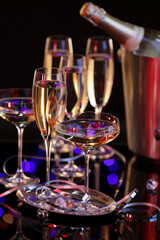 Champagne in glasses and party streamers on black mirror surface