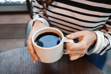 Businesswoman having coffee break at wooden table in cafe, closeup
