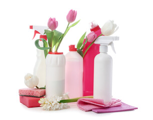 Bottles of detergents with rags, sponges and spring flowers on white background