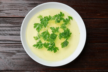 Tasty chicken bouillon in bowl on wooden table, top view