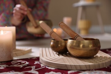 Woman with singing bowls and burning candles indoors, closeup