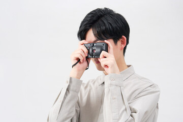 Fototapeta premium フィルムカメラのファインダーを覗く男性 白背景