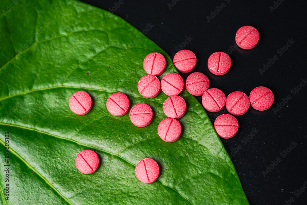 Wall mural Red herbal capsule pill with herbs and natural green betel leaf background