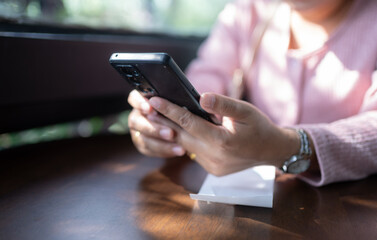Close-up of hands of an Asian girl holding and looking at her smart phone in the office. Communication and online business concept.