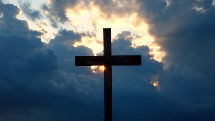 Christian cross silhouette against dramatic sunset sky with divine light rays. Religious symbol for Easter, Good Friday and Christmas. Sacred spiritual background