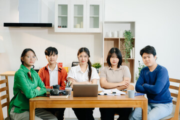 Teamwork and creativity with young adults collaborating on laptops and tablets in a cozy