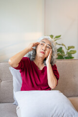 Unhappy Retired Senior Woman holding her head with pain expression . Face of senior woman suffering...