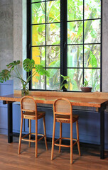 Empty wooden table and chairs in coffee shop cafe. Seat and wood counter bar against glass window. Cafe design.