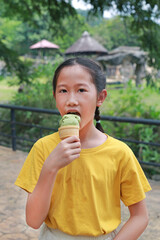 Fototapeta premium Asian young girl child eating tasty green tea ice cream in the garden.