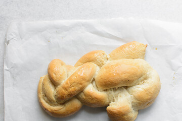 Overhead view of freshly baked challah on white parchment paper, top view of homemade braided challah, homemade challah baking fail