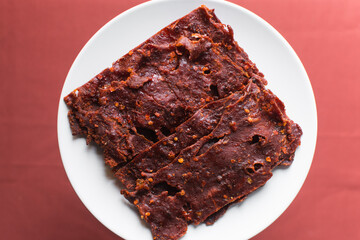 Overhead view of Nigerian kilishi on a white plate, top view of nigerian spicy beef jerky, flatlay of dried beef suya