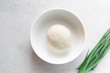Overhead view of chinese scallion pancake dough on white countertop, top view of homemade scallion pancake dough, process of making cong you bing