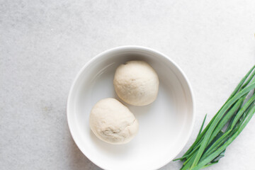 Fototapeta premium Overhead view of chinese scallion pancake dough on white countertop, top view of homemade scallion pancake dough, process of making cong you bing