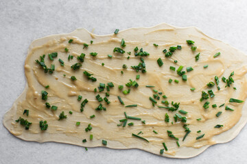 overhead view of sliced scallions on thinly rolled dough, process of making scallion pancakes or cong you bing