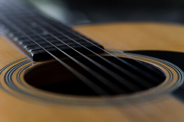 A close up of acoustic guitar with blurry background.