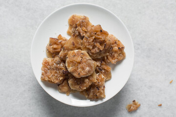 Overhead view of nigerian coconut candy on a white plate, top view of candied coconuts discs, flatlay of bukayo candy or coconut drops