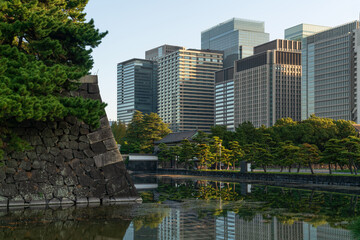 Skyscrapers of the Marunouchi business district in Chiyoda Ward against the background of the Hamaguri-moat and the ramparts of the Imperial Palace on a sunny day, Tokyo, Japan