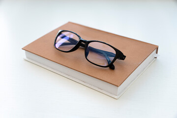 Reading glasses with books on white table