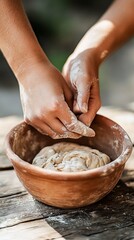 Fototapeta premium Hands kneading dough in clay bowl outdoors
