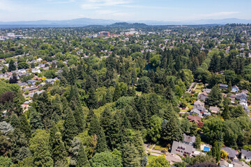 Aerial drone view of Northeast Portland, Oregon, showcasing residential homes, tree-lined streets, urban landscape, and cityscape with Mount Hood and Mount St. Helens visible in the background