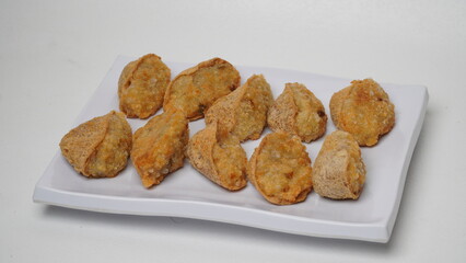A plate of fried tahu walik is placed on a white base and background (isolated white).