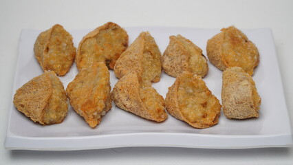 A plate of fried tahu walik is placed on a white base and background (isolated white).