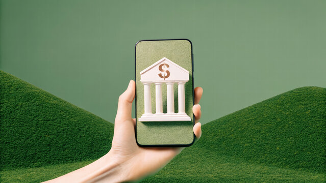 hand holding smartphone displaying digital bank icon on green background, symbolizing modern banking and finance. image conveys innovation and accessibility in financial services
