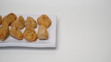 A plate of fried tahu walik is placed on a white base and background (isolated white).