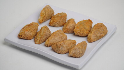 A plate of fried tahu walik is placed on a white base and background (isolated white).